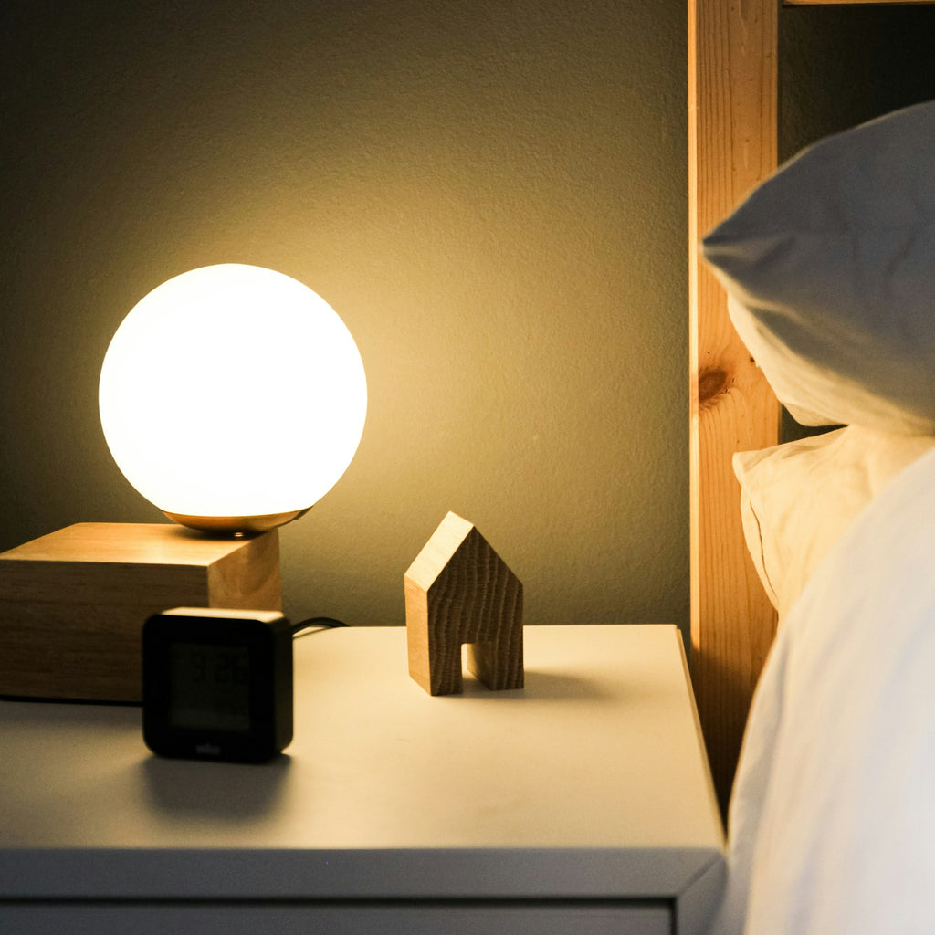 Compact globe table lamp styled beside a bed