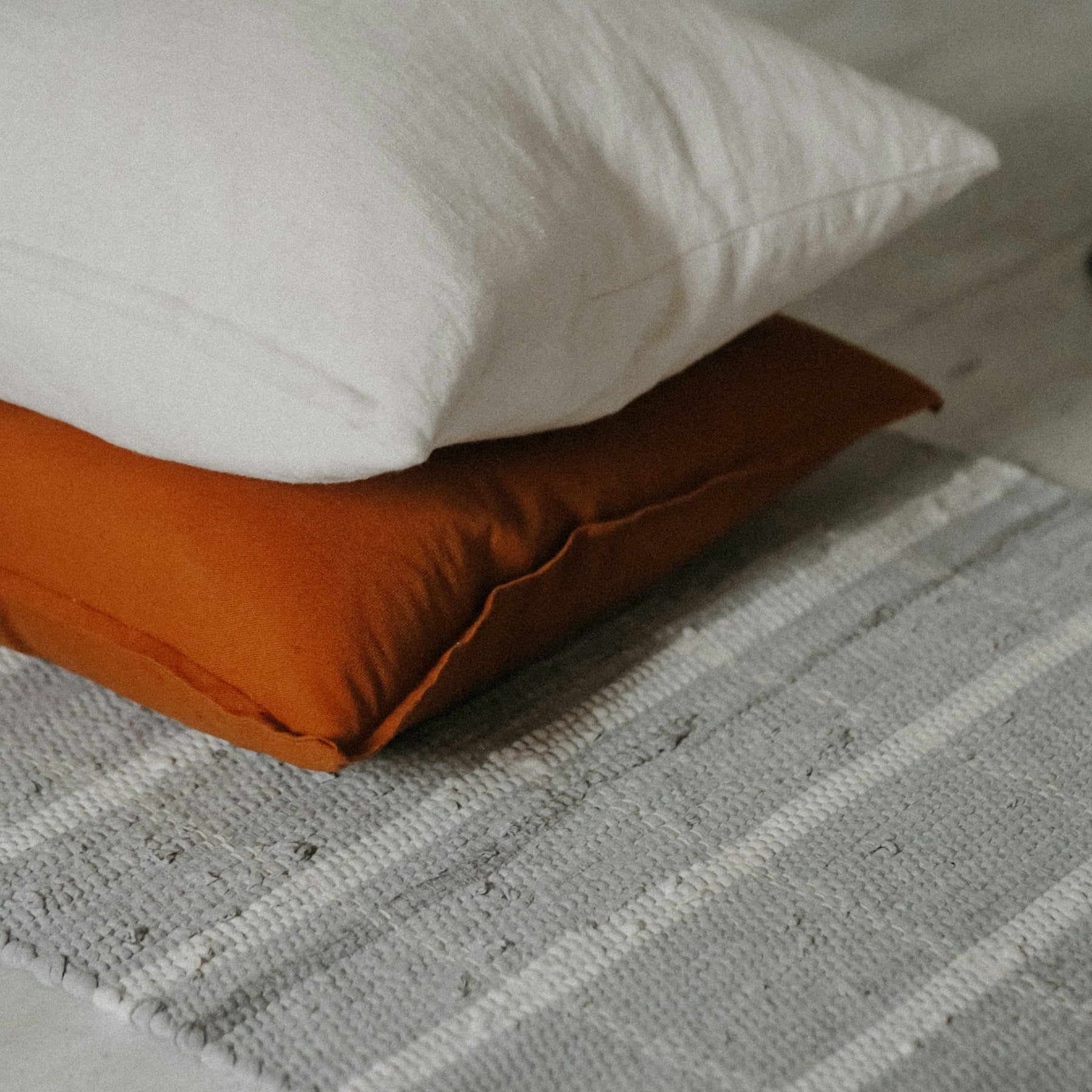 Layered Vale cushions styled on a neutral bed